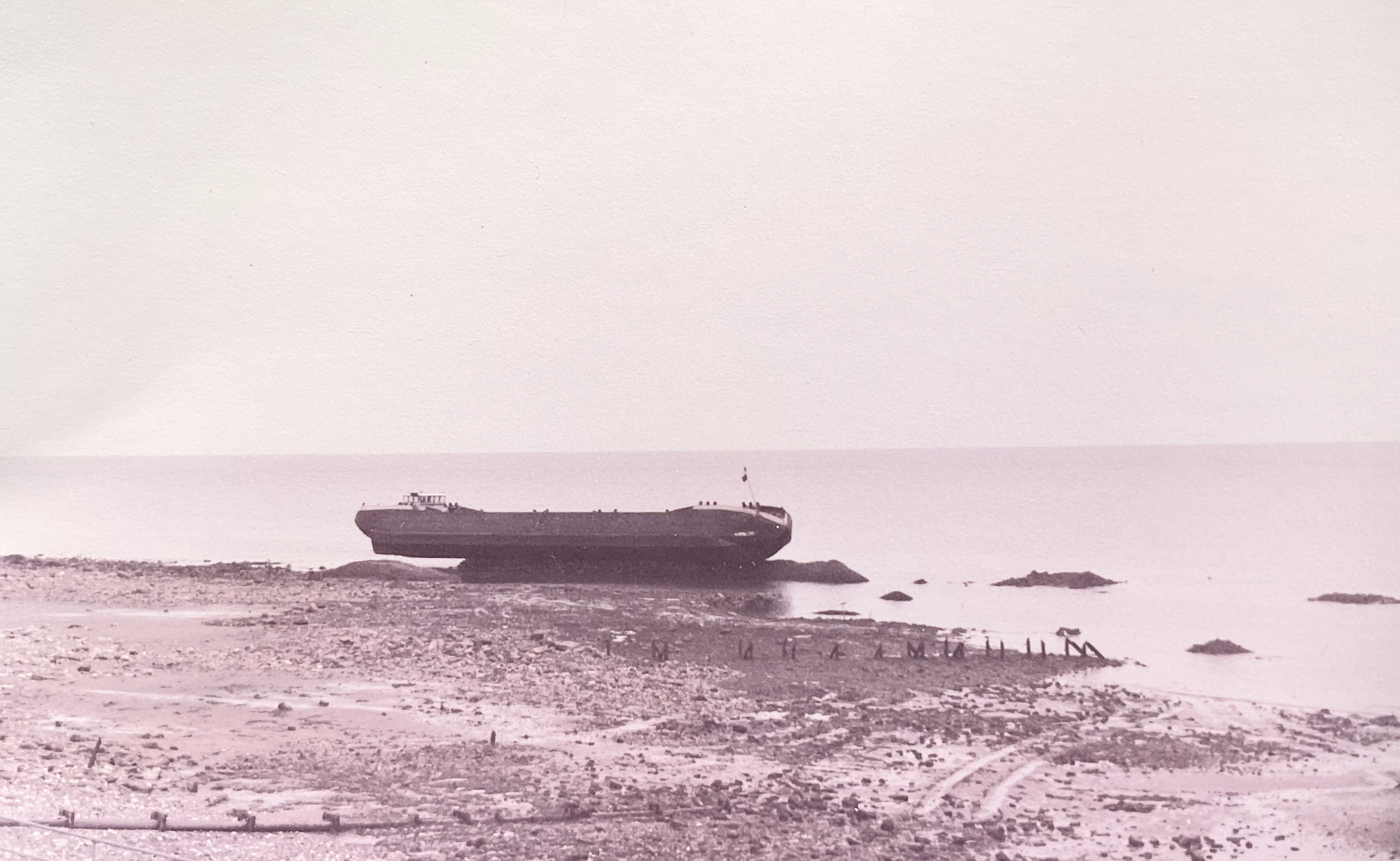 A barge balanced on the rocks it had dropped but on which it is now grounded