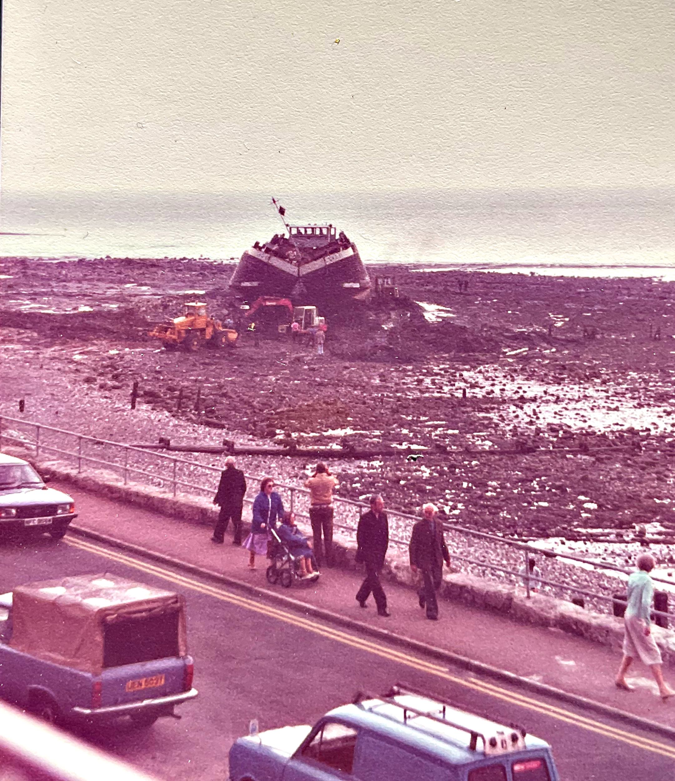 Diggers clearing rocks and sand from around a grounded barge to assist in its release.