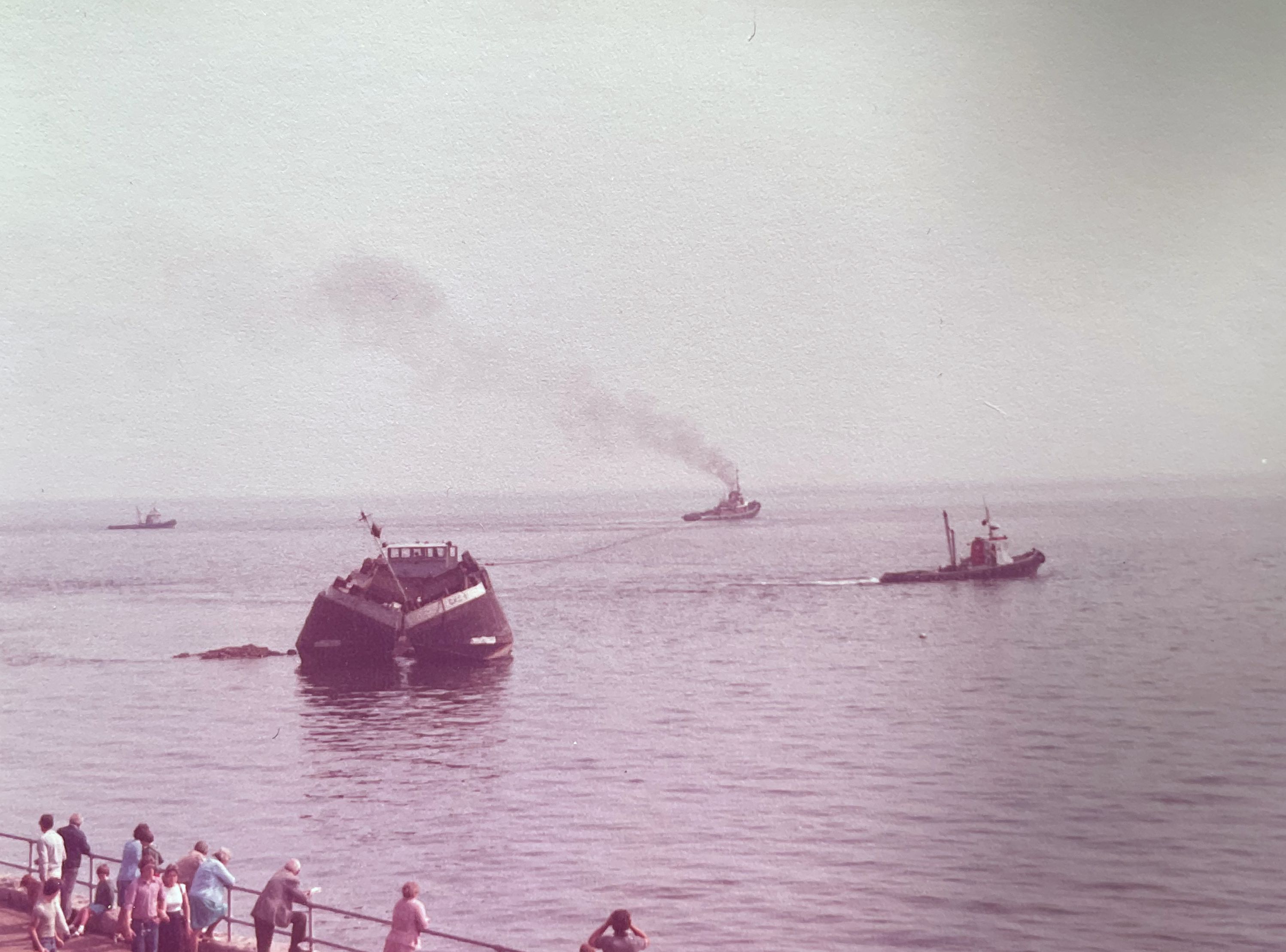 Two tugs attempt to re-float a gounded barge.